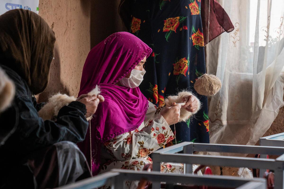 Women working in a wool spinning center, established by a UNHCR livelihood grant beneficiary who used the grant money to purchase machines and raw materials, providing job opportunities for women.