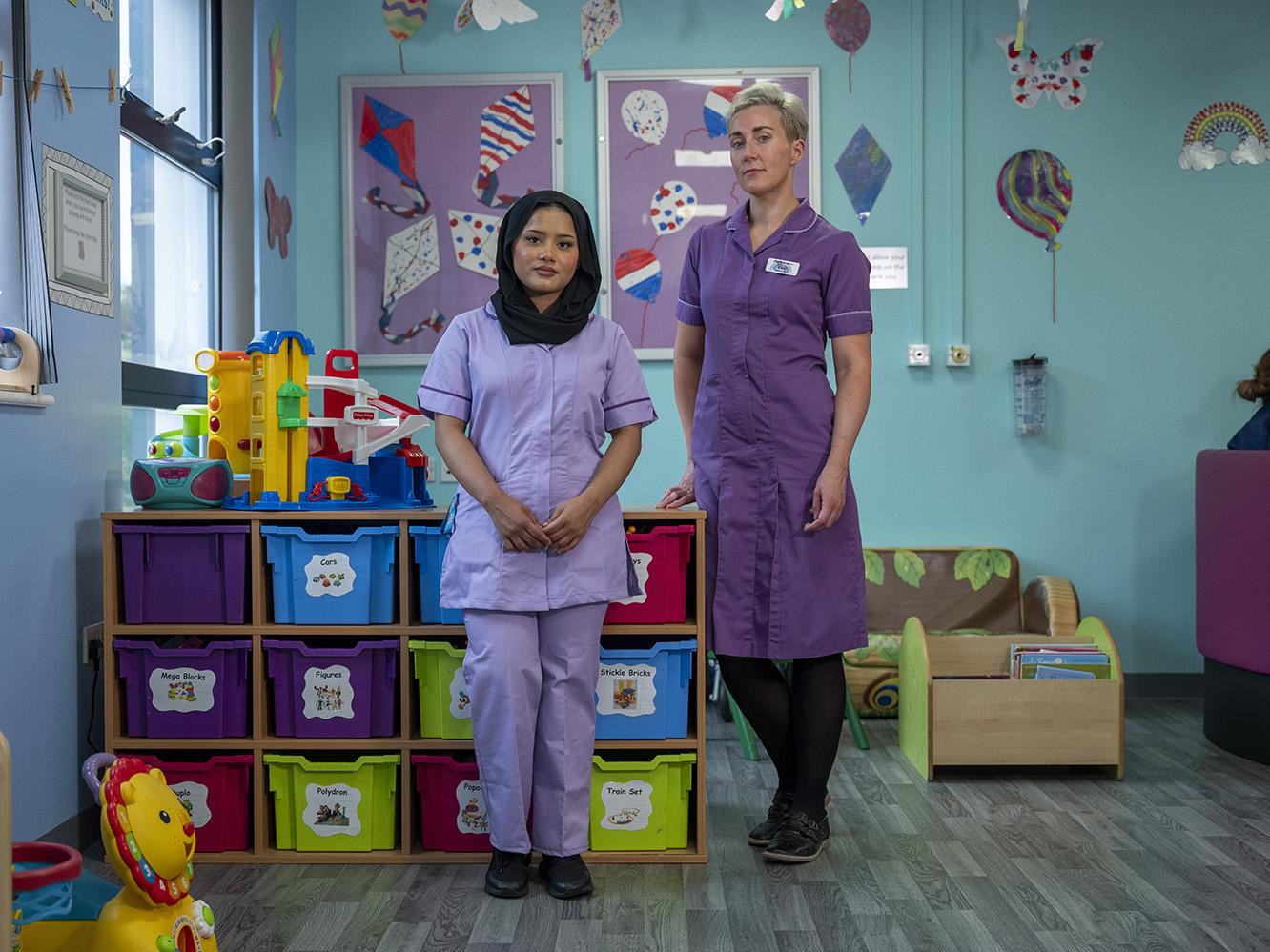 Kismat Ara (left) with nurse Vikki-Marie Deegan in the Children’s Ward at Bradford Royal Infirmary. ; Kismat Ara (21), of the Rohingya ethnic group, was resettled to the city of Bradford with her family in 2009 from Cox’s Bazar, Bangladesh. She graduated in 2023 from the University of Bradford with a degree in Child Nursing and has just begun working as a Staff Nurse at Bradford Royal Infirmary’s Children’s Ward, encouraged by the welcoming environment and supported by her fellow nurses and colleagues
